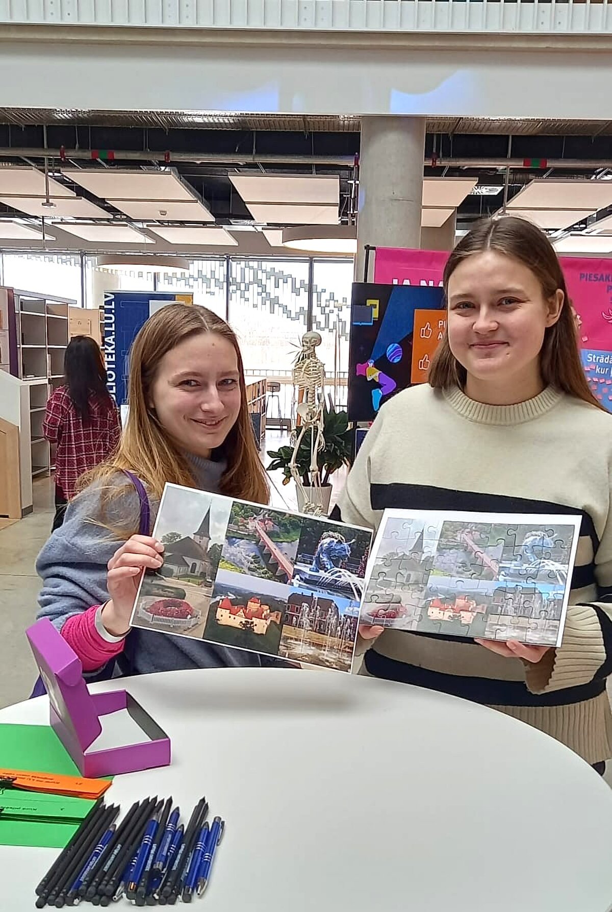 Vidusskolnieces dalās priekā par puzles salikšanu Divas vidusskolnieces dalās priekā par puzles salikšanu